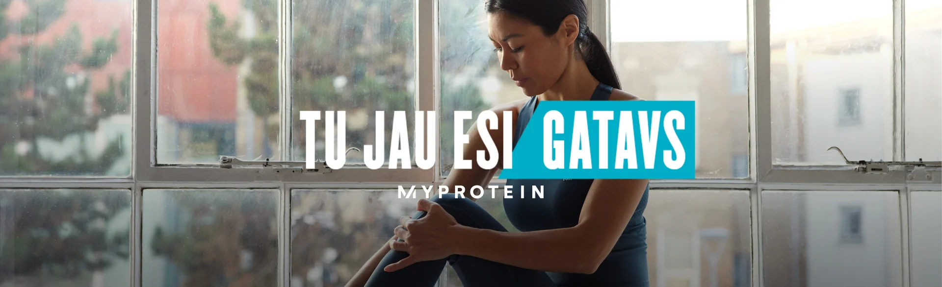 A woman wearing MP gym clothing sat on a window ledge stretching with the text 'You're Already Ready - MYPROTEIN' overlaying the image.